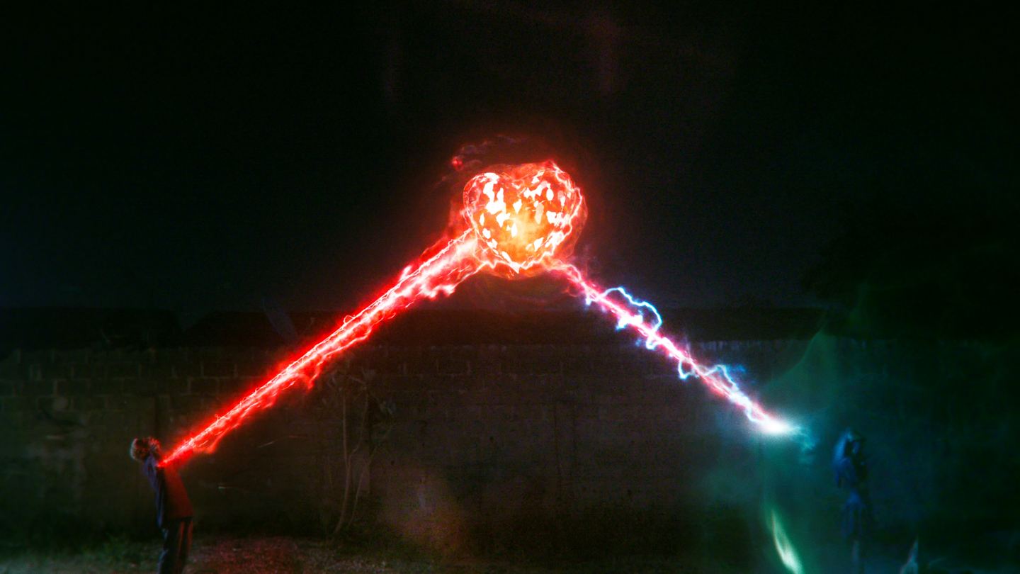 A long-exposure light painting: a burning red streak arcs across a dark wall and knots into a bright flare at its centre.